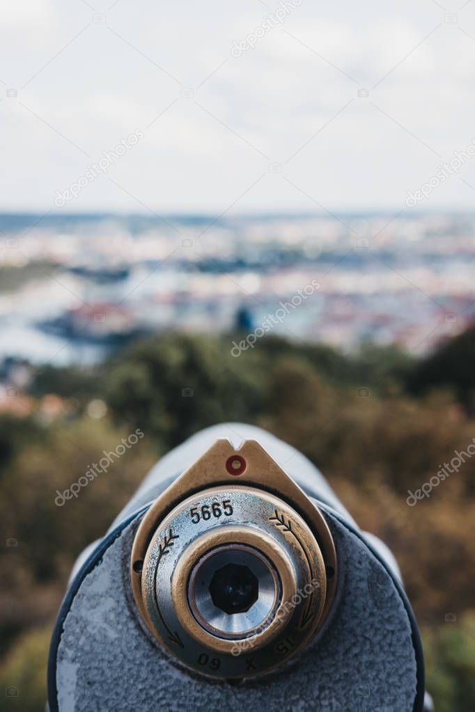 Coin operated binoculars on the viewing platform on Petrin Tower, Prague, in summer, the blurred city background.