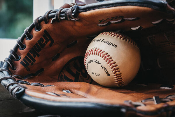 Лондон, Великобритания - 3 января 2019 года: Закрыть белый бейсбольный мяч внутри загорелой бейсбольной перчатки. Возникнув в Англии в 18 веке, бейсбол является широко популярным видом спорта во многих странах мира
.