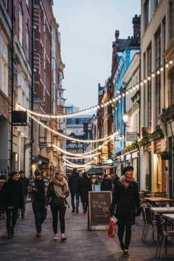 London, UK - January 5, 2019: People walking under the strings of lights in Kingly Street. The street runs north to south form Liberty's and parallel and between Regent Street and Carnaby Street. clipart