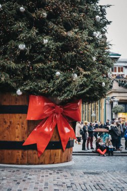 Londra, İngiltere - 5 Ocak 2019: Covent Garden Market, Londra, İngiltere'de en popüler turistik yerleri önünde bir hediye etiketi ile bir tencerede dev Noel ağacı tarafından yürüyüş insanlar.