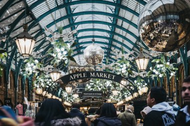 Londra, İngiltere - Ocak 5,2019: Londra, İngiltere'de en popüler turist insanlar, Noel süsleri ve Covent Garden pazarında dev baubles süslenmiş Apple Pazar işareti altında siteleri.
