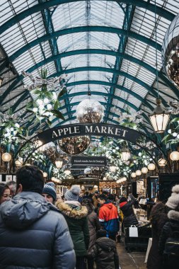 Londra, İngiltere - Ocak 5,2019: Londra, İngiltere'de en popüler turist insanlar, Noel süsleri ve Covent Garden pazarında dev baubles süslenmiş Apple Pazar işareti altında siteleri.