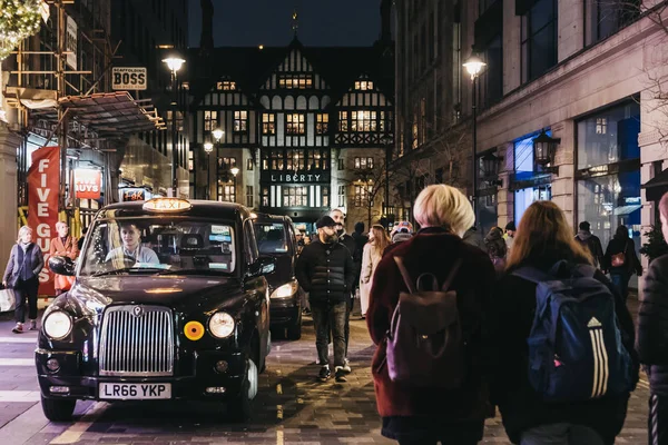 2019年1月5日 人们走过停在伦敦阿盖尔街的黑色出租车 伦敦自由百货公司的背景 黑色出租车是伦敦的标志性象征 — 图库照片