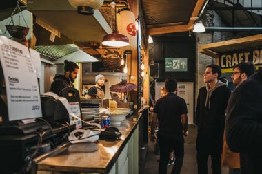 London, UK - January 13, 2019: People at Hermanos Taco House stand in Mercato Metropolitano, sustainable community market in London focused on revitalising the area and protecting environment. clipart