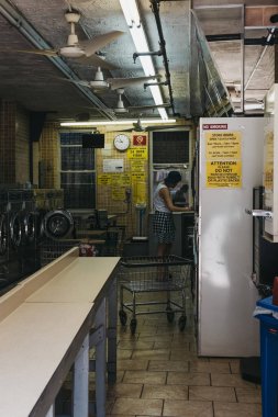 New York, USA - May 30, 2018: People inside laundromat in New York, the city where most locals dont have the advantage of in unit washers and dryers. clipart