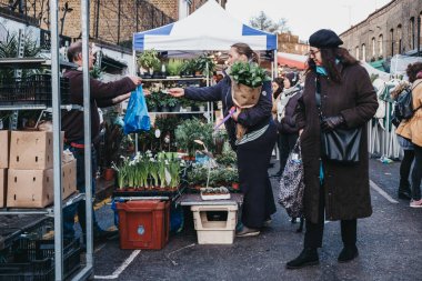 London, UK - February 3, 2019: People buying flowers from a market stalls at Columbia Road Flower Market, a street market in East London that is open every Sunday. clipart