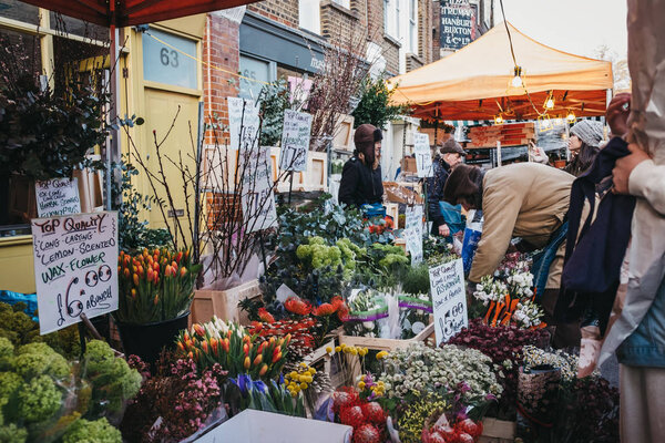 London, UK - February 3, 2019: People buying flowers from a market stalls at Columbia Road Flower Market, a street market in East London that is open every Sunday.