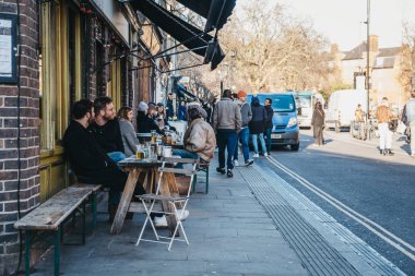 Londra, İngiltere - 03 Şubat 2019: Broadway Market, Hackney, Londra, İngiltere, kalbinde bir alışveriş caddesi üzerinde bir açık bir kafede masada oturan insanlar.