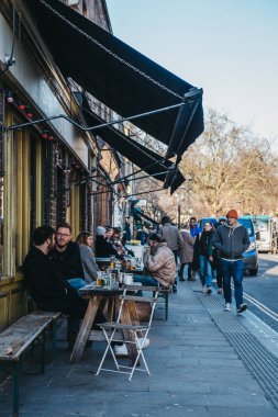Londra, İngiltere - 03 Şubat 2019: Broadway Market, Hackney, Londra, İngiltere, kalbinde bir alışveriş caddesi üzerinde bir açık bir kafede masada oturan insanlar.