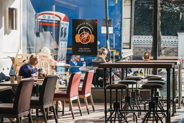 Mulher bebendo café e lendo em Pret a Manger, Londres, Reino Unido . — Fotografia de Stock