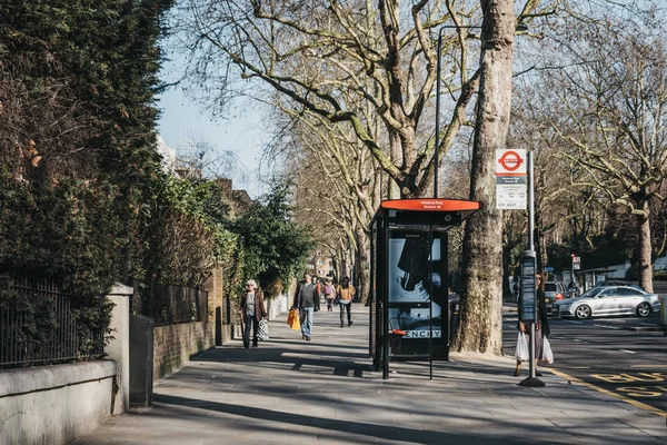 Frau wartet in holland park, kensington und chelsea auf einen bus, — Stockfoto