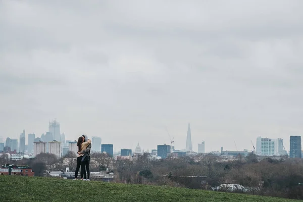 Couple hug in a park, London skyline on the background, UK. — Stock Photo, Image