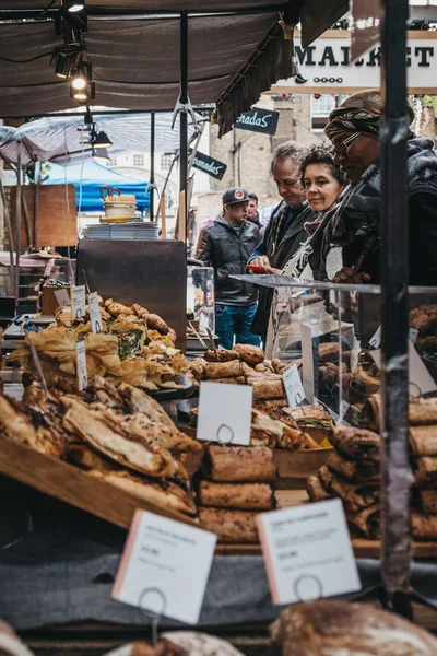 Gente comprando pan fresco y pasteles en un puesto de mercado en Gr — Foto de Stock