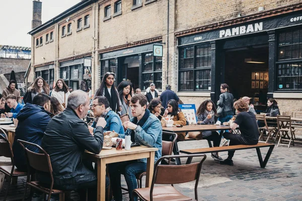 Menschen sitzen an Tischen im Freien im Camden Market, London, u — Stockfoto