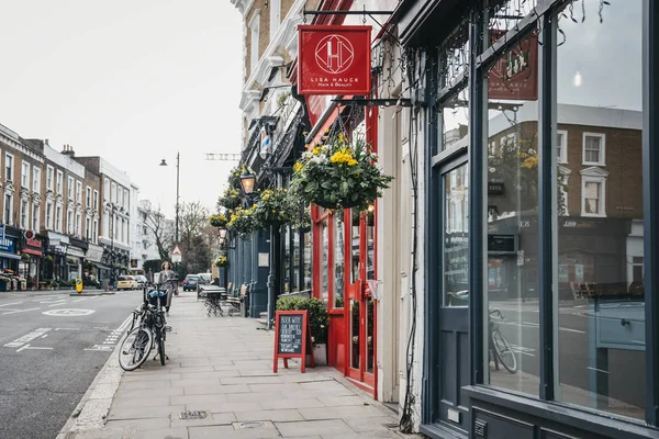 Rows of shops in Belsize Park, London, UK, woman walking on the — Stock Photo, Image