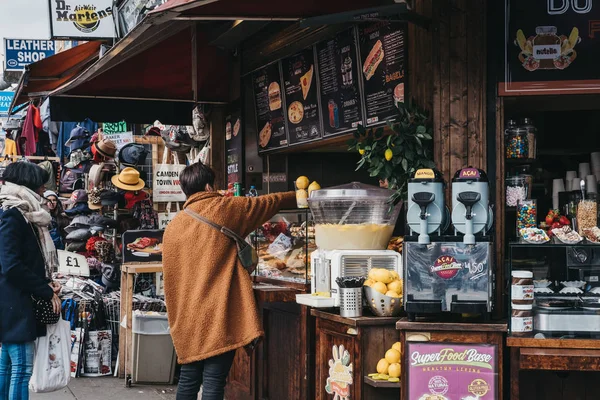 Mujer pidiendo comida de un puesto dentro de Camden Market, Londres, U — Foto de Stock