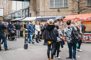 Brick Lane, Londra, Ingiltere üzerinde gıda tezgahları geçmiş yürüyüş insanlar.