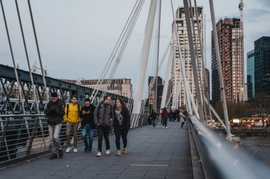 Millennium Bridge'de yürüyen insanlar, Londra, İngiltere, alacakaranlıkta.