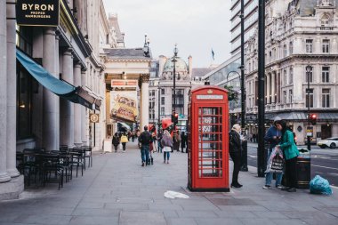 Westmi Şehri Haymarket'te kırmızı telefon kulübesinden geçen insanlar