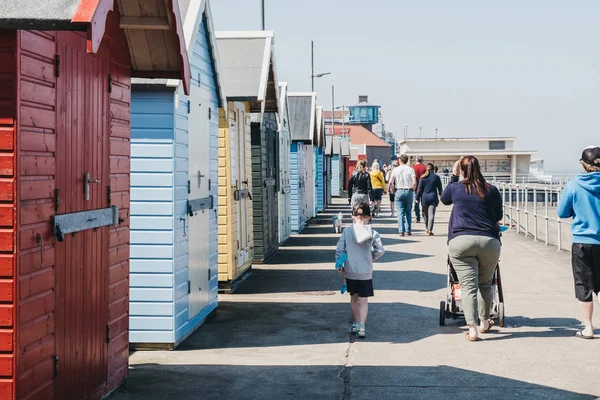 Family walking by colourful beach huts by the sea in Sheringham, — Stock Photo, Image