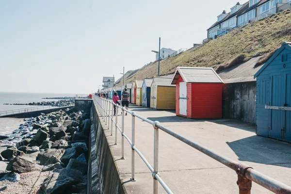 Az emberek séta színes strand kunyhók a tenger mellett Sheringham, — Stock Fotó