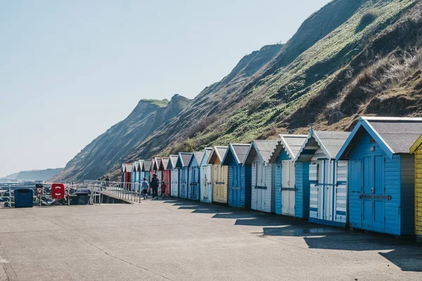 Människor som går genom färgglada strandhyddor vid havet i Sheringham, — Stockfoto