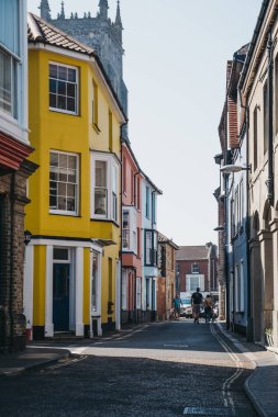 Cromer, Norfolk, İngiltere'de renkli evlerin önünden geçen insanlar.