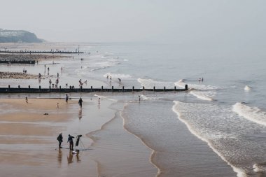 Cromer, Norfolk, İngiltere'de bir plajda güneşli bir günün tadını çıkaran insanlar.