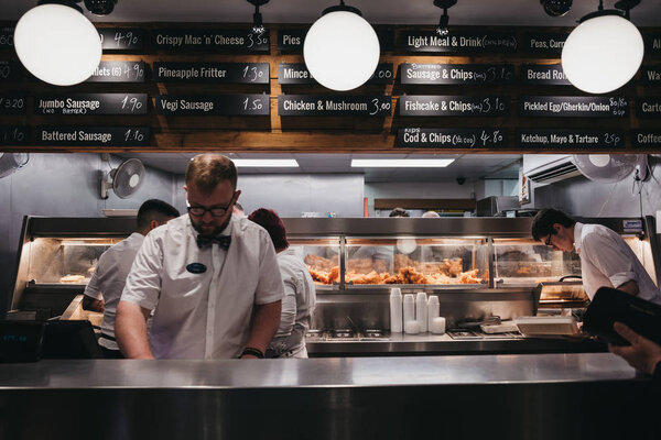 Staff serving fish and chips inside French's fish and chip shop 
