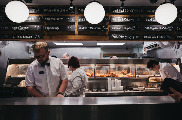 Staff serving fish and chips inside French's fish and chip shop 