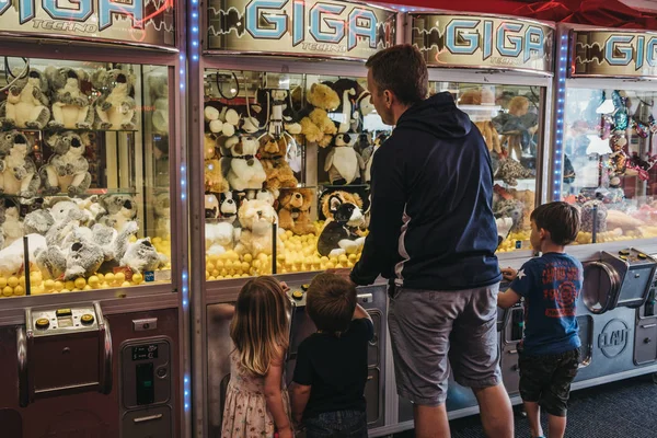 Father and kids trying to win a soft toy from machine at the arc — Stock Photo, Image