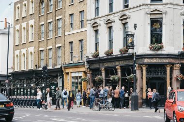People standing and drinking outside The Ten Bells pub in Shored clipart