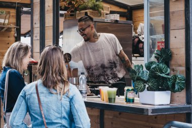 Kadınlar Spitalfields Market 'teki bir tezgahtan yemek sipariş ediyorlar, Lon.