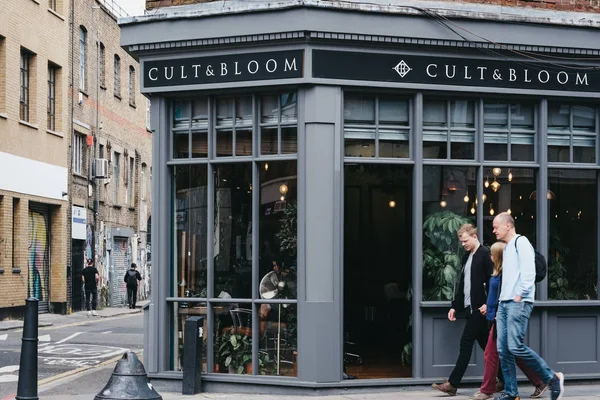 Shoreditch, Londo'daki Cult & Bloom kuaför salonunun önünden geçen insanlar