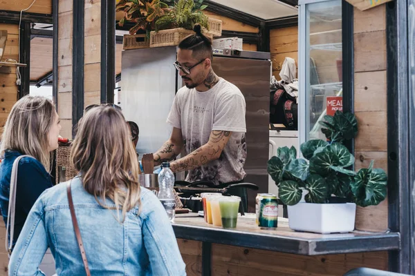 Kadınlar Spitalfields Market 'teki bir tezgahtan yemek sipariş ediyorlar, Lon.