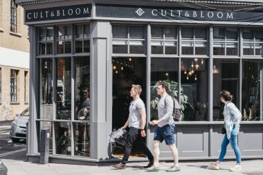 Shoreditch, Londo'daki Cult & Bloom kuaför salonunun önünden geçen insanlar