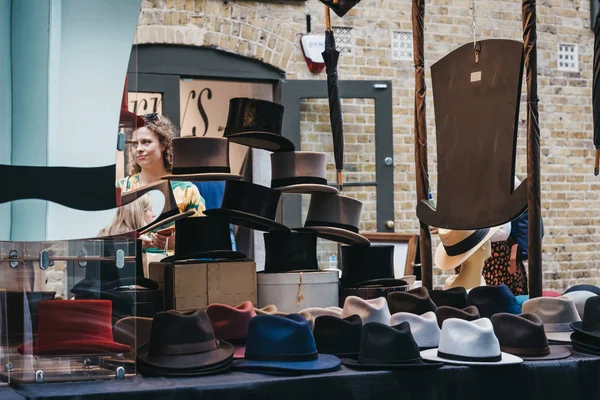 Mensen kijken naar hoeden op kraam binnen Spitalfields Market, Lond — Stockfoto