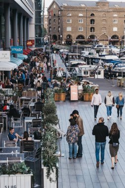 St. Katharine Docks'taki restoran ve kafelerin önünden geçen insanlar
