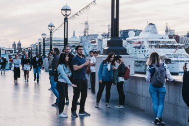 İnsanlar yürüyen ve Thames Riverside i tarafından akşam karanlığı resim çekerken