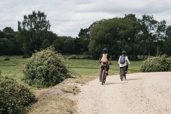 Gente en bicicleta en un camino de grava dentro de New Forest, Dorset, Reino Unido . — Foto de Stock