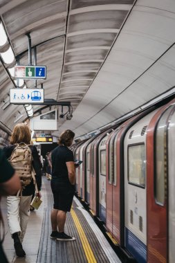 Londra Metro İstasyonu platformunda insanlar, tren geçen b
