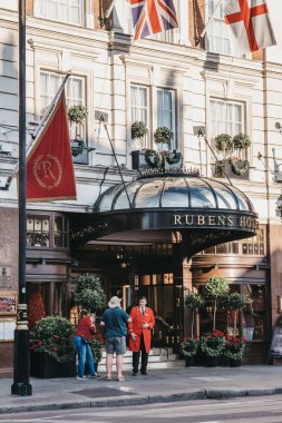 Saray otelinde Rubens dışında uşak ile konuşan insanlar 