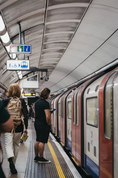 People on a London Underground station platform, train passing b — Stock Photo, Image