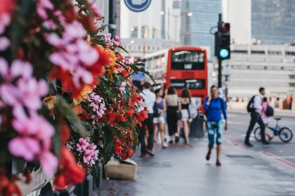 Άνθρωποι αγνώστων στοιχείων περπατούν σε ένα δρόμο στο Λονδίνο, UK, άνθη — Φωτογραφία Αρχείου