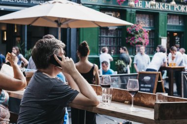 Adam cep telefonu, B içinde bir pub masasında oturan konuşuyor