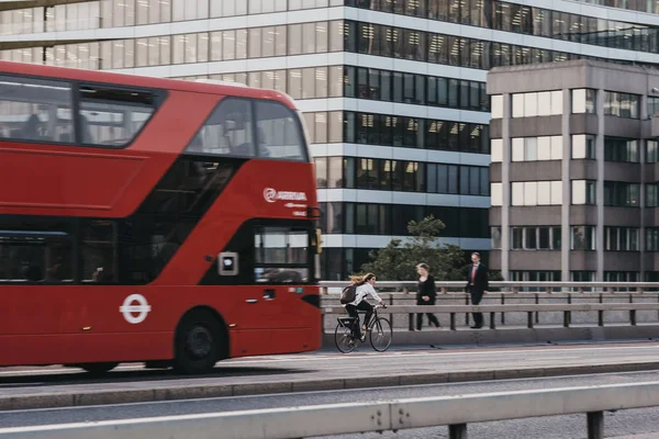 Mujer ciclista y autobús en London Bridge, Reino Unido, panorámica, desenfoque de movimiento — Foto de Stock