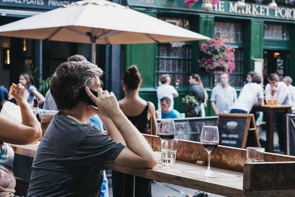 Mann telefoniert, sitzt an Kneipentisch im Haus — Stockfoto