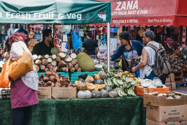 Mulheres compram frutas e legumes frescos no Brixton Market, Londo — Fotografia de Stock