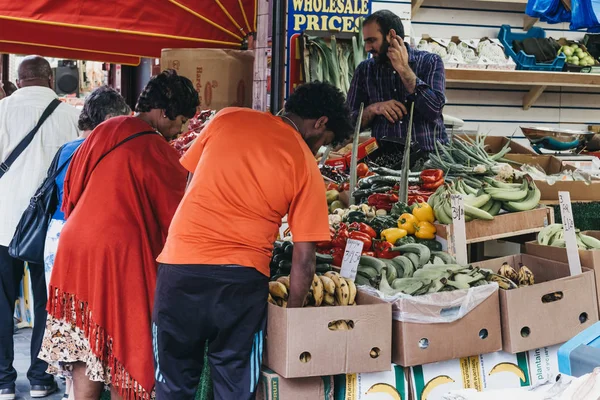 As pessoas compram frutas e legumes frescos de uma banca de mercado no Br — Fotografia de Stock