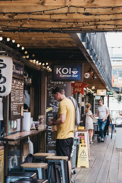 Homem encomendar comida de KOI Ramen em Pop Brixton, Londres, Reino Unido . — Fotografia de Stock